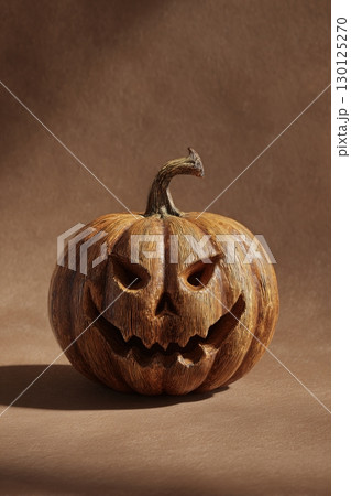 Hand-Carved Jack-o'-Lantern with Detailed Textures on Brown Background 130125270