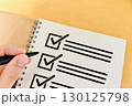 チェックリストに書き込む人の手 130125798