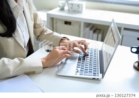 Close up of businesswoman in beige blazer typing on laptop keyboard 130127374