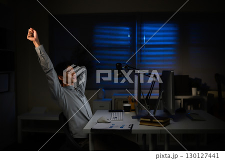 Overworked worker taking a break from computer tasks, stretching after long hours of screen time Overworked worker taking a break from computer tasks, stretching after long hours of screen time 130127441