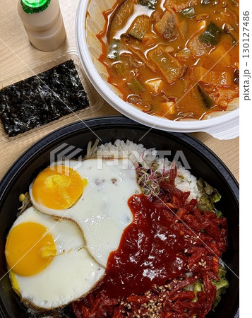 Yukhoe bibimbap with fresh veggies, rice, seasoned raw beef, raw egg yolk, and gochujang offering a bold mix of flavors and textures in a classic Korean dish. Yukhoe bibimbap with fresh veggies, rice, seasoned raw beef, raw egg yolk, and gochujang offering a bold mix of flavors and textures in a classic Korean dish. 130127486