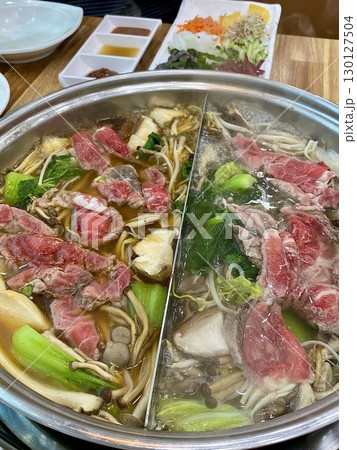A steaming pot of shabu-shabu with thinly sliced meat, fresh vegetables, and dipping sauces. This Japanese hotpot dish offers a healthy and interactive dining experience. A steaming pot of shabu-shabu with thinly sliced meat, fresh vegetables, and dipping sauces. This Japanese hotpot dish offers a healthy and interactive dining experience. 130127504