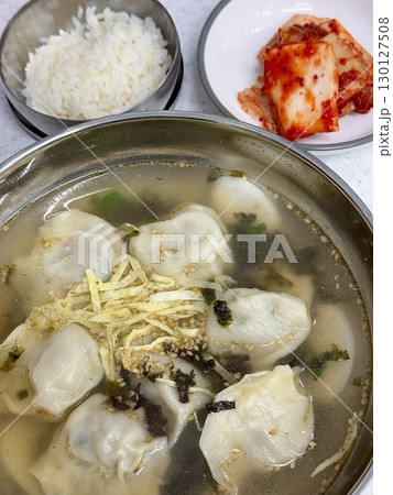Warm, comforting bowl of Mandu-guk, a traditional Korean soup featuring dumplings in a savory broth. Often enjoyed during celebrations, this hearty dish is filled with rich flavors and textures. 130127508