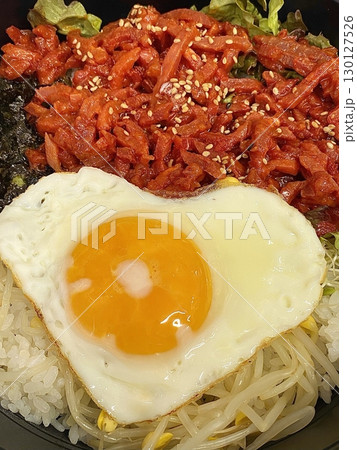 Yukhoe bibimbap with fresh veggies, rice, seasoned raw beef, raw egg yolk, and gochujang offering a bold mix of flavors and textures in a classic Korean dish. 130127526