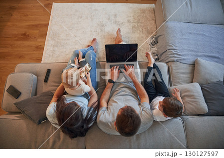 Top view, using laptop. Parents with two little boys kids are together in domestic room Top view, using laptop. Parents with two little boys kids are together in domestic room 130127597