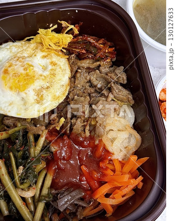 Bibimbap, a vibrant Korean rice dish topped with a variety of seasoned vegetables, gochujang, and a fried egg, often accompanied by sliced meat. Mixed together, it creates a flavorful and balanced. Bibimbap, a vibrant Korean rice dish topped with a variety of seasoned vegetables, gochujang, and a fried egg, often accompanied by sliced meat. Mixed together, it creates a flavorful and balanced. 130127633