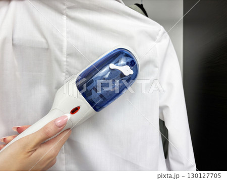Woman ironing clothes with steam iron at wardrobe. Clothes care and garment steaming. Fashion, laundry, household chores, wrinkle removal. Business and casual clothing care 130127705