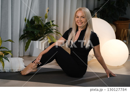 Stylish woman practicing yoga in a serene indoor space with soft lighting and plants, showcasing relaxation and wellness amid modern decor elements Stylish woman practicing yoga in a serene indoor space with soft lighting and plants, showcasing relaxation and wellness amid modern decor elements 130127784