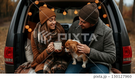 Cozy autumn vibes captured in a heartfelt moment. A couple enjoys warm drinks with their adorable dog 130127960