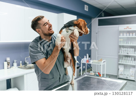 Playful mood, having fun. Dog in veterinarian clinic with male doctor Playful mood, having fun. Dog in veterinarian clinic with male doctor 130128117