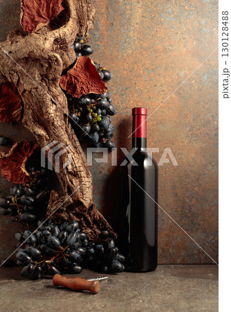 Bottle of red wine with blue grapes on a rusty background. Bottle of red wine with blue grapes on a rusty background. 130128488