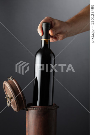 Sommelier places a bottle of red wine in an old wooden box. 130128499