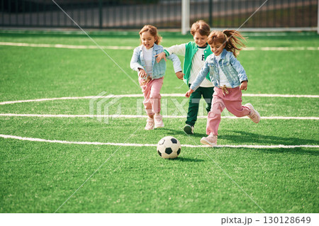 Active weekend. Kids are having fun on the green soccer field together Active weekend. Kids are having fun on the green soccer field together 130128649