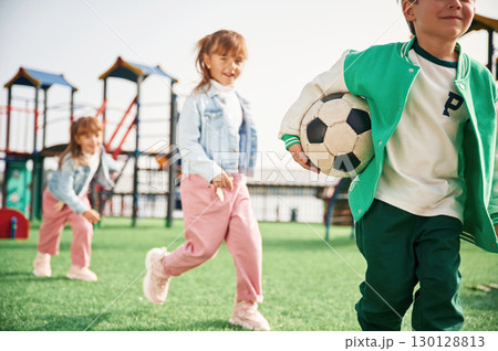 Holding soccer ball in hand, running. Kids are having fun on the playground Holding soccer ball in hand, running. Kids are having fun on the playground 130128813