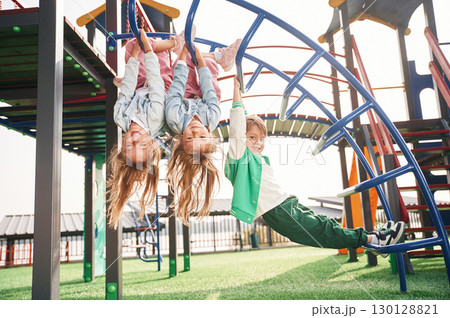 Hanging upside down. Kids are having fun on the playground 130128821