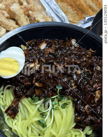 A bowl of jajangmyeon featuring chewy noodles coated in rich black bean sauce, topped with diced pork and vegetables. This iconic Korean-Chinese dish offers a savory and hearty flavor. A bowl of jajangmyeon featuring chewy noodles coated in rich black bean sauce, topped with diced pork and vegetables. This iconic Korean-Chinese dish offers a savory and hearty flavor. 130129093