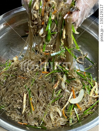 A vibrant plate of japchae featuring stir-fried glass noodles, colorful vegetables, and tender slices of meat, all coated in a savory-sweet soy-based sauce. A classic Korean favorite! 130129117
