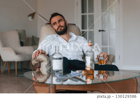 Life crisis. With whiskey. Upset young man drinker alcoholic is indoors 130129386