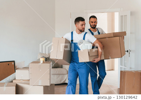 Front view, holding stuff. Two moving service employees in a room Front view, holding stuff. Two moving service employees in a room 130129642