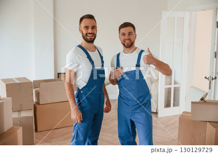 Standing and posing. Two moving service employees in a room 130129729