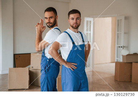 Standing and posing. Two moving service employees in a room 130129730
