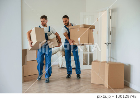 Boxes in hands. Two moving service employees in a room Boxes in hands. Two moving service employees in a room 130129748