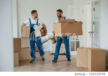 Boxes in hands. Two moving service employees in a room Boxes in hands. Two moving service employees in a room 130129749