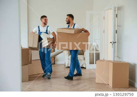 Boxes in hands. Two moving service employees in a room Boxes in hands. Two moving service employees in a room 130129750