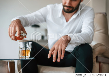 Pouring the whiskey into the glass. Upset young man drinker alcoholic is indoors Pouring the whiskey into the glass. Upset young man drinker alcoholic is indoors 130129861