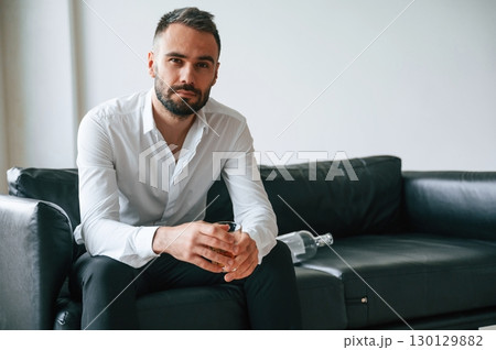 Sitting on he sofa. Upset young man drinker alcoholic is indoors 130129882