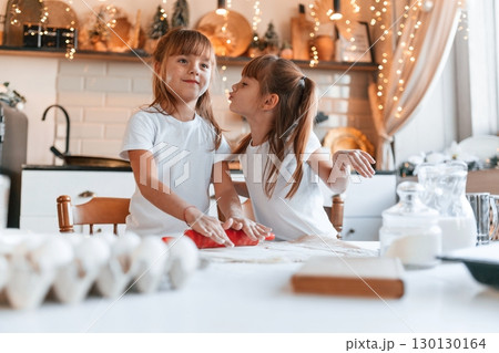Festive interior. Two little girls are preparing food on the kitchen with garlands Festive interior. Two little girls are preparing food on the kitchen with garlands 130130164