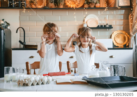 Holding forms for the best rolled sugar cookies. Two little girls are preparing food on the kitchen with garlands 130130205