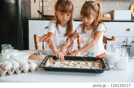 Raw sweet cookies. Two little girls are preparing food on the kitchen with garlands 130130217
