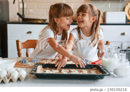 Smiling, playful mood. Two little girls are preparing food on the kitchen with garlands 130130218