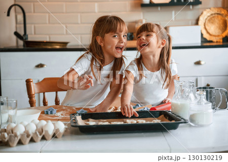 Smiling, playful mood. Two little girls are preparing food on the kitchen with garlands 130130219