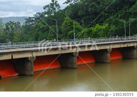 Red floodgate dam structure over muddy river water. 130130355