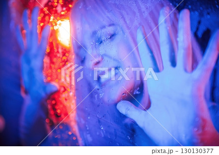 Hands are on the surface. Stylish woman with white hair is behind wet transparent plastic sheet 130130377