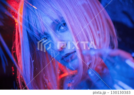 Posing for camera. Stylish woman with white hair is behind wet transparent plastic sheet 130130383