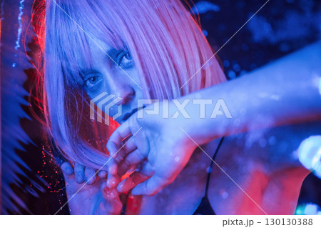 Futuristic style. Stylish woman with white hair is behind wet transparent plastic sheet Futuristic style. Stylish woman with white hair is behind wet transparent plastic sheet 130130388