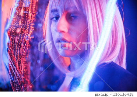 Posing, calm facial expression. Stylish woman with white hair is behind wet transparent plastic sheet 130130419