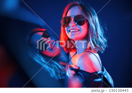 Reflection on the left side. Cool young woman portrait in neon colors 130130445