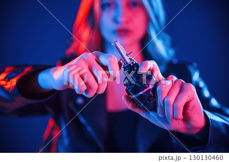 Holding grenade. Cool young woman portrait in neon colors Holding grenade. Cool young woman portrait in neon colors 130130460