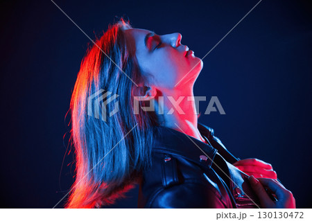 Against dark blue background. Cool young woman portrait in neon colors 130130472