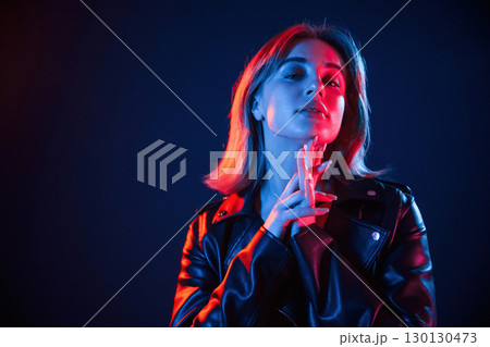 Against dark blue background. Cool young woman portrait in neon colors 130130473