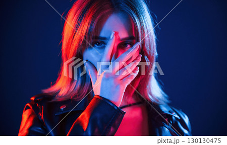 Against dark blue background. Cool young woman portrait in neon colors 130130475