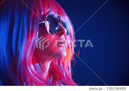White hair of medium length. Woman is in studio with neon colors 130130480