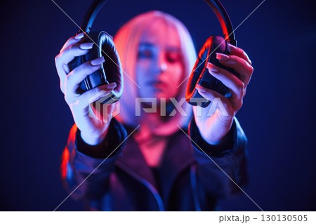 Showing headphones. Woman with white hair is in studio with neon colors 130130505