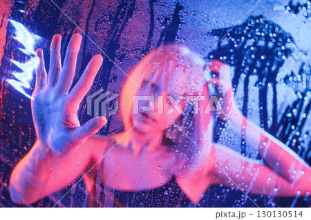 Trapped inside, with hands on surface. Stylish woman with white hair is behind wet transparent plastic sheet 130130514