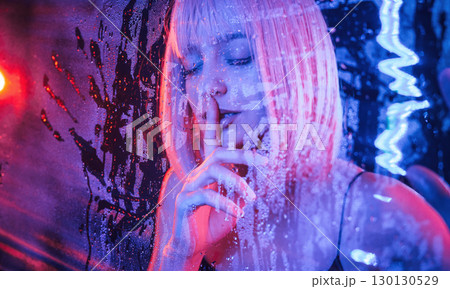 Silence gesture, be quiet, by finger. Stylish woman with white hair is behind wet transparent plastic sheet Silence gesture, be quiet, by finger. Stylish woman with white hair is behind wet transparent plastic sheet 130130529