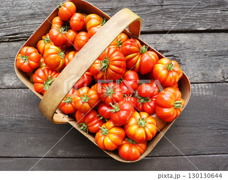 Red tomatoes in basket on wooden table	 130130644